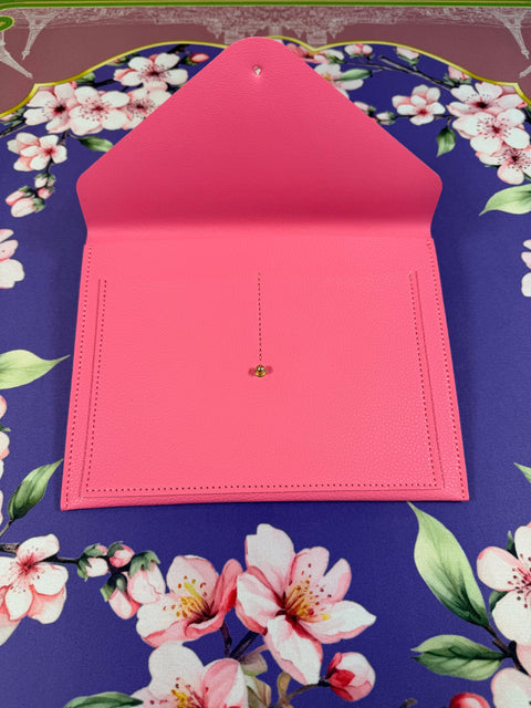 a pink envelope on a floral surface