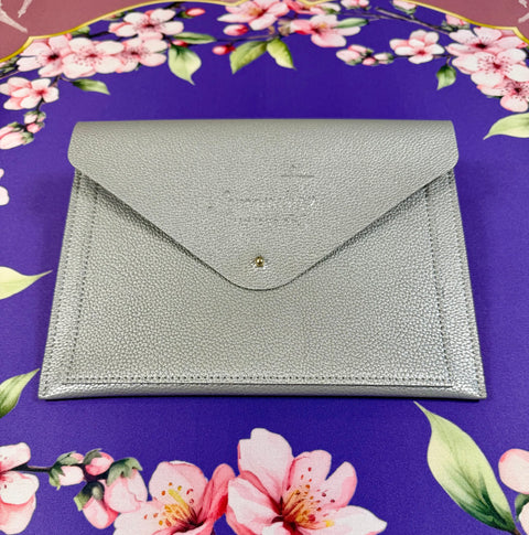 a silver envelope on a purple tablecloth with pink flowers