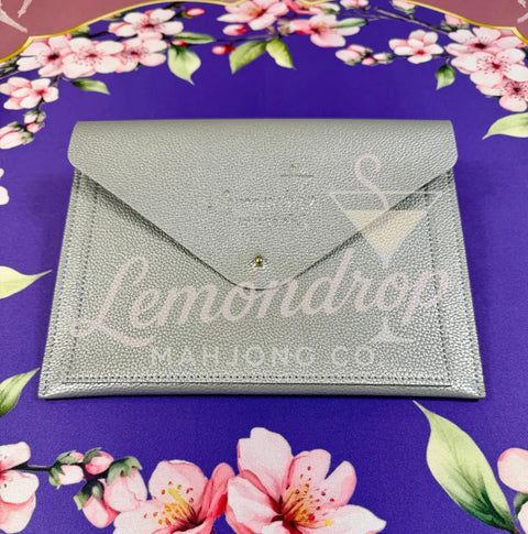 a silver envelope on a purple tablecloth with pink flowers