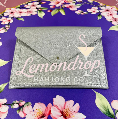 a silver envelope on a purple tablecloth with pink flowers