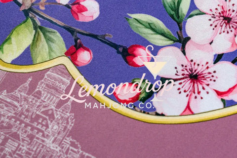 Floral print fabric featuring pink cherry blossoms on a purple background with golden trim.